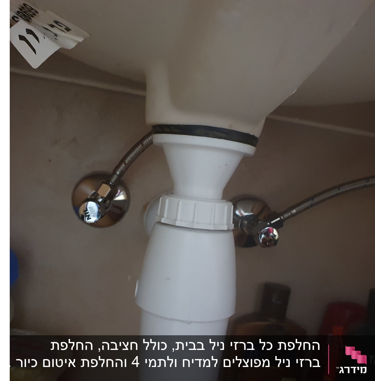 צינור פלסטיק לבן עם חיבורים מתכתיים מתחת לכיור